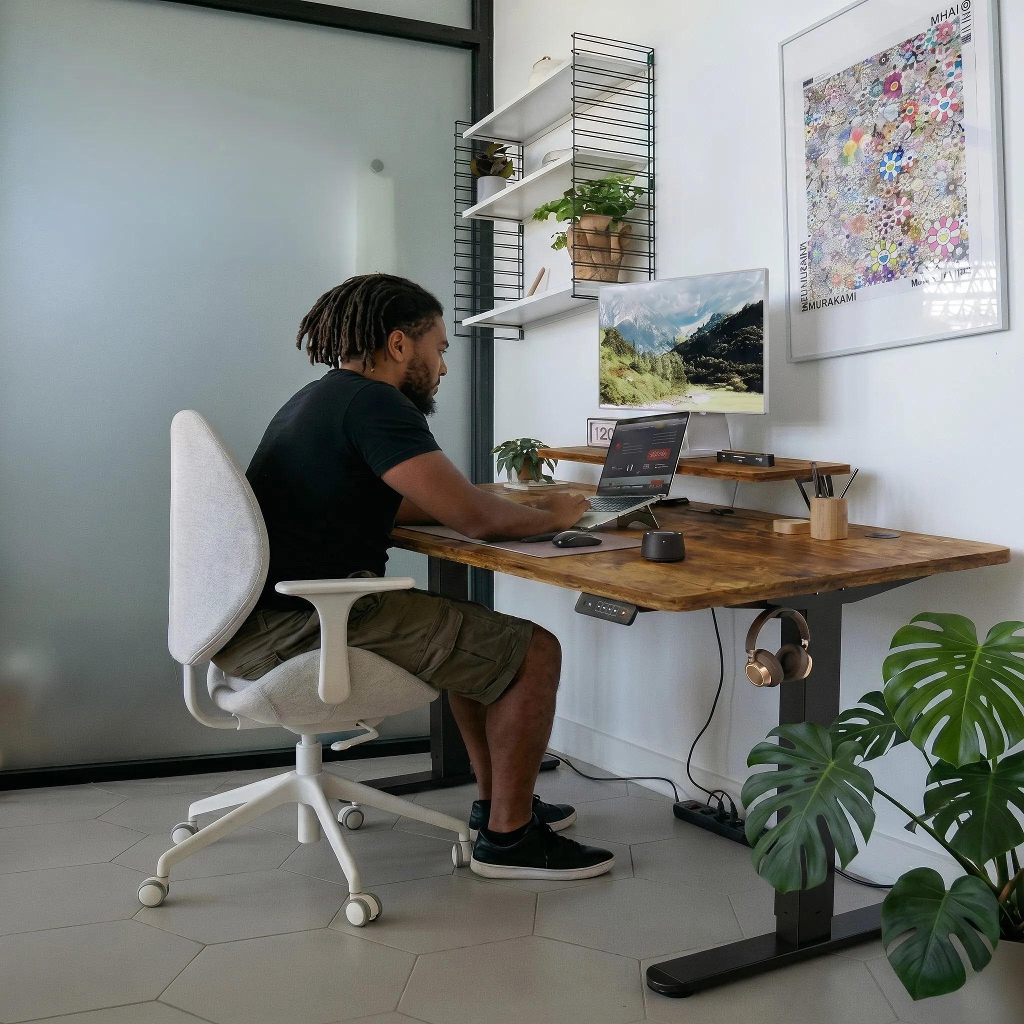 Utilisateur travaillant assis à un bureau réglable en hauteur robuste conçu pour supporter jusqu'à 60 kg de matériel.