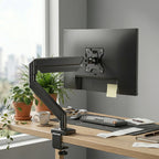 Support articulé pour écran d'ordinateur noir libérant l'espace sur un bureau en bois grâce à sa fixation robuste sur le bord de la table.